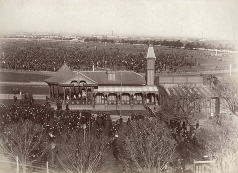 Race day at Flemington Race Course, showing crowds in centre of track and back of grandstand, 1890–1900
