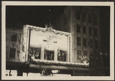 Floodlit decorated facade of Sands & McDougall printers and lithographers in Spencer Street, Melbourne, 1954