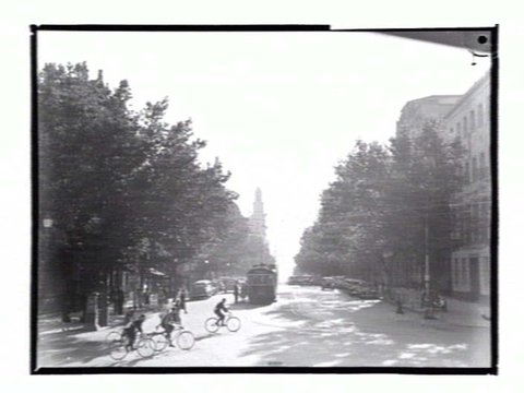 View down Collins Street from Spring Street, with bicyclists crossing the street, 1936–39
