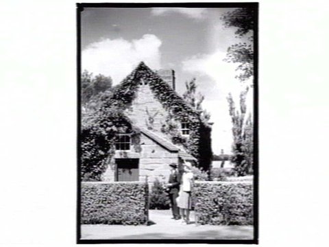Couple outside Cook's Cottage, Fitzroy Gardens, 1936–39