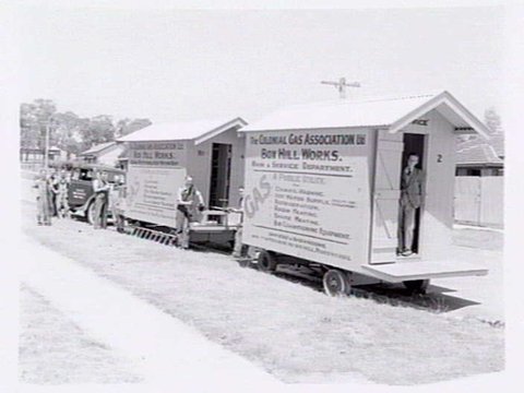 Workmen standing outside two Colonial Gas Association caravans from the Box Hill works, 1937–40