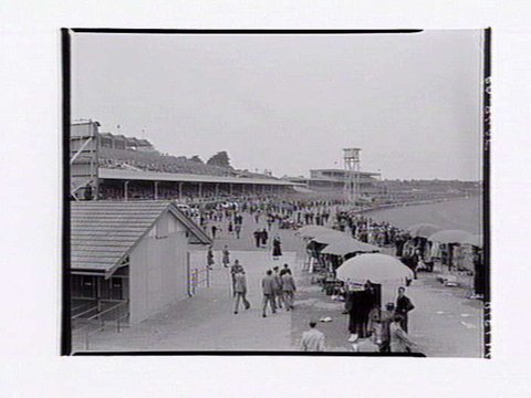 Flemington Racecourse, showing racetrack, members stand and large crowds of people, 1949