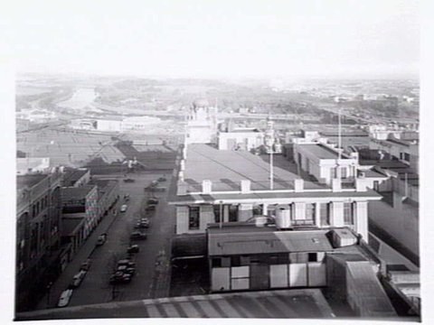 View over rooftops from corner of Russell and Flinders Streets, Melbourne, showing Flinders Street Station Rail Yards, Yarra River and Ball & Welsh Ltd, c. 1943