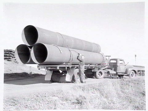 A man securing tubes on the back of a truck belonging to Humes Ltd, Dynon Road, Footscray, c. 1954