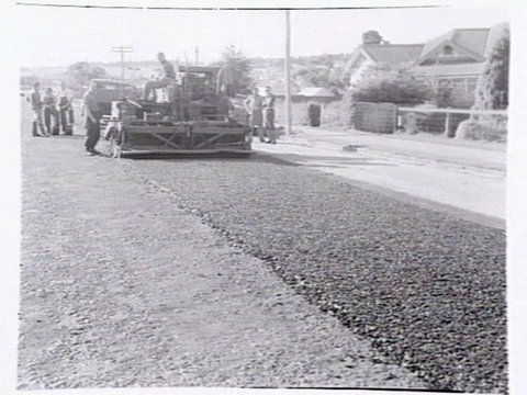 Roadmaking by Albion Quarrying P/L, showing machine laying asphalt and section of road in Heidelberg yet to be resurfaced, 1950