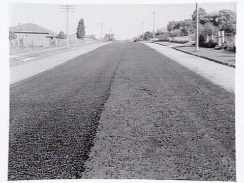Roadmaking by Albion Quarrying P/L, showing machine laying asphalt and section of road in Heidelberg yet to be resurfaced, 1950