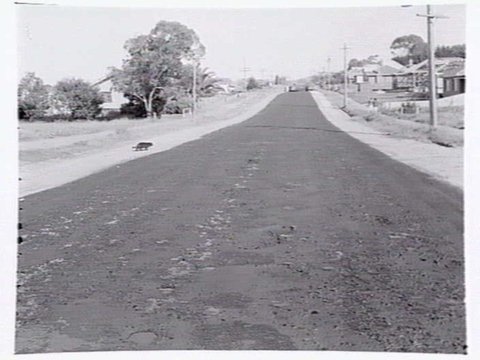 Roadmaking by Albion Quarrying P/L, showing machine laying asphalt and section of road in Heidelberg yet to be resurfaced, 1950