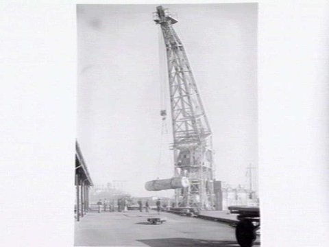Melbourne Harbour Trust 40 ton floating crane lifting a boiler onto or from a low loader at wharf, 1949