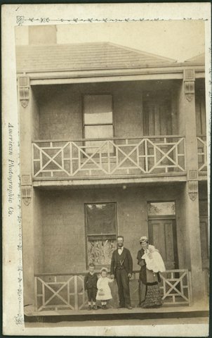 Unidentified family standing in front of a double storey terrace house, Capel Street, West Melbourne, 1882–84