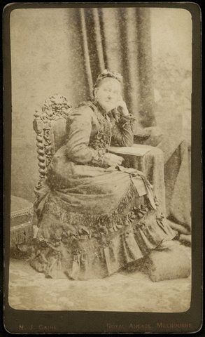 Studio portrait of lady, sitting, to left, whole-length, Royal Arcade, Melbourne, 1876–77