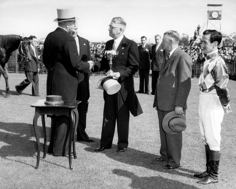 Mr A. E. Underwood, owner of Cup winner, Wodalla, receives the Melbourne Cup from the Governor-General (Sir William Slim), at his right is jockey Jack Purtell and next to him, trainer R. Sinclair, 1950–56