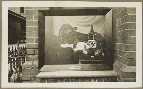 Picture on outer wall, possibly at Bryant & May, Richmond, showing dog smoking pipe, bottle of West End Dinner Ale and packet of Bryant & May matches with caption 'Good Companions', 1920–33