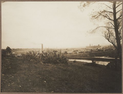 View from near Kensington Road, South Yarra, looking west, with Bryant and May at left of image; in the foreground the Yarra River and the billabong to the east of Mary Street, Richmond. The new Church Street Bridge under construction can be seen behind the aloe, 1920–26