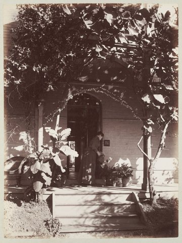 Woman watering pot plants on verandah at Ethelred, Hawthorn, 1884–94