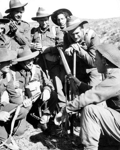 Reinforcements listen eagerly while Pte V. Kelly, of Elwood, Vic., (right) puts them in the picture, 1950