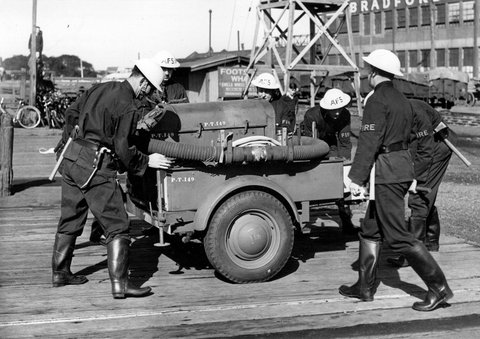 Footscray Auxiliary Firemen inspecting hose carriage and trailer pump during World War II, c. 1942