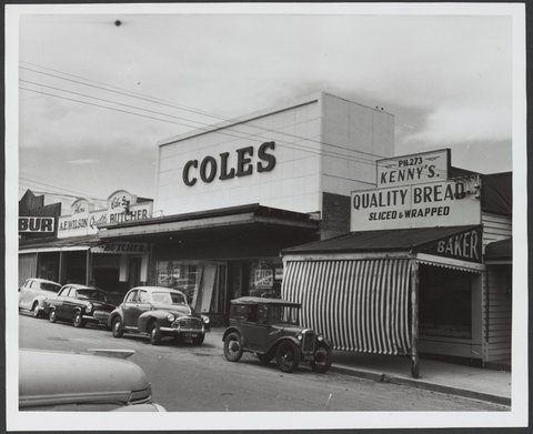 Row of shops with cars parked at curb including baker with striped awning adjoining Coles Croydon Store No. 204, 1935