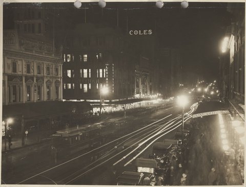 Night view of Bourke Street pedestrians trams lights and neon Coles sign Store No. 12, 1920s