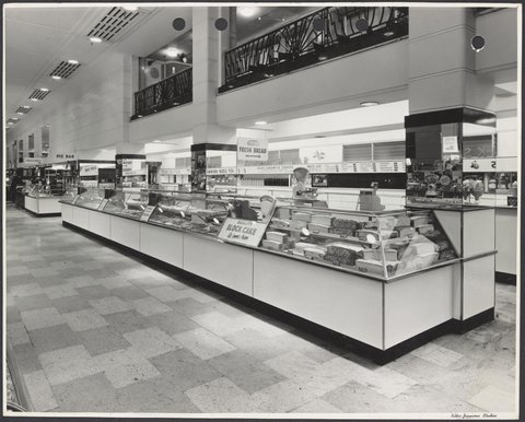 Glass cabinets displaying cakes with sandwich bar behind and cafeteria on level above Coles Bourke Street Store No. 12, 1940–47