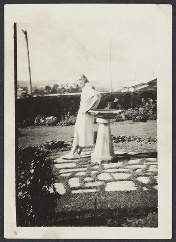 Lorna Williams at E. B. Coles Kew leaning against a sun dial in a garden, 1930–40
