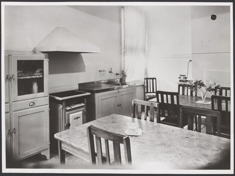 Kitchen with two wooden dining tables, chairs, stove, sink and cupboards 411-415 Sydney Road Brunswick Store No. 3, 1947