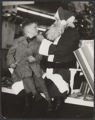 Boy sitting on "Santa's" knee inside Mantons Bourke Street store, 1942–51