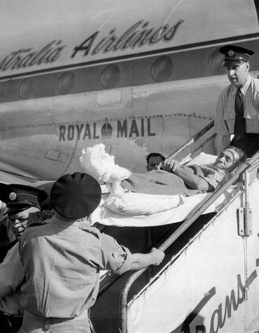 Pte. Norman Taugge on stretcher being carried from T.A.A. aircraft, Essendon, Victoria, c. 1950