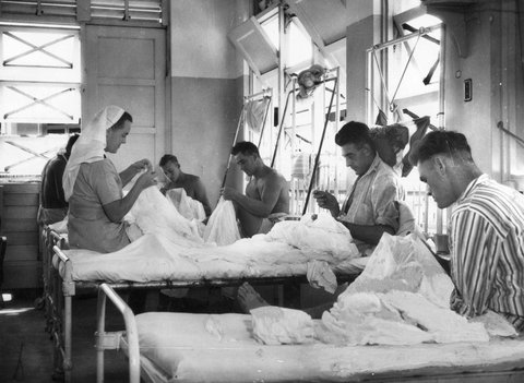 Sister D. WILSON (Melbourne) leads some of the boys in a sewing bee mending mosquito nets, c. 1943
