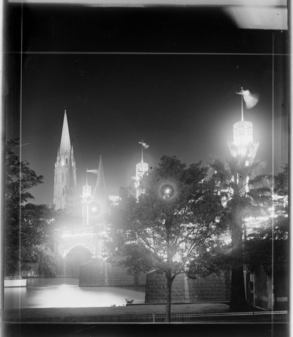 Melbourne city and illuminated Centenary pylons on Princes Bridge, taken from south side of Yarra River, where Arts Centre now stands, 1934–35